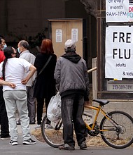 People look over a sign advertising a free flu shot clinic provided by Cedars-Sinai Hospital and Good Samaritan Hospital in the parking lot of Immanuel Presbyterian Church in Los Angeles on October 21, 2020.
Credit: Genaro Molina/Los Angeles Times/Getty Images