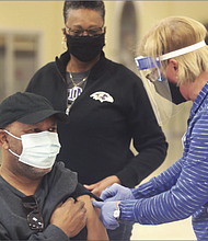 Sylvia Jones, 68, watches as her husband, George Jones, 69, receives his first shot of the COVID-19 vaccine. The couple, members of Second Baptist Church of South Richmond, were inoculated during a vaccine event held at the church by the Richmond and Henrico health districts.