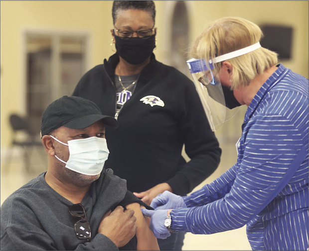 Sylvia Jones, 68, watches as her husband, George Jones, 69, receives his first shot of the COVID-19 vaccine. The couple, members of Second Baptist Church of South Richmond, were inoculated during a vaccine event held at the church by the Richmond and Henrico health districts.