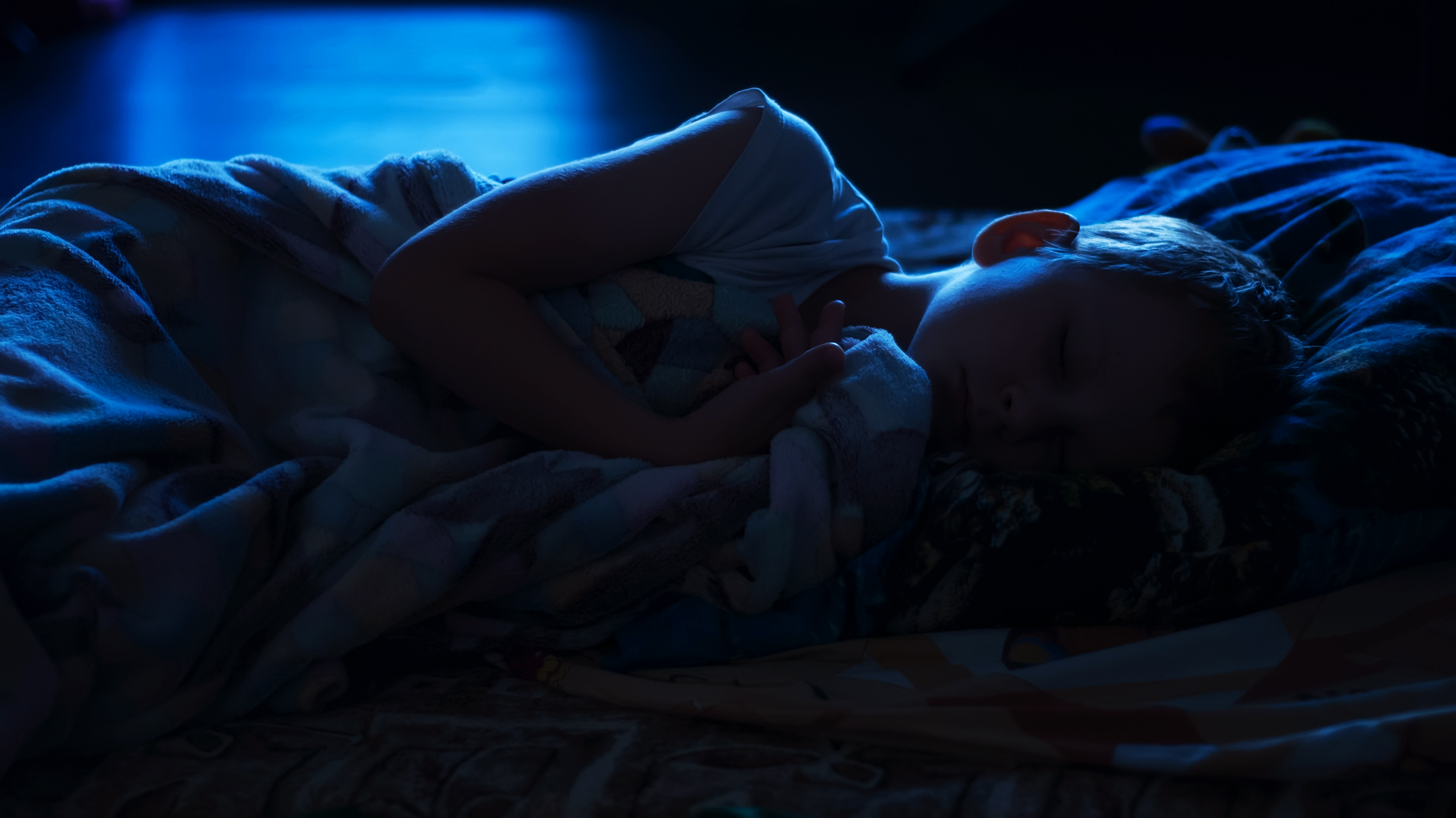 Спящий ребенок в кроватке ночью