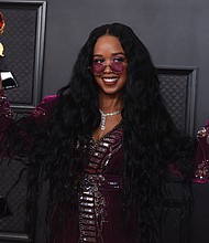 H.E.R. poses in the press room with the award for song of the year for “I Can’t Breathe” and best R&B song.