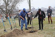 Mayor Levar M. Stoney, right, gets a hand from John Harris of the city Department of Parks, Recreation and Community Facilities, in planting an oak tree overlooking the city at the Powhatan Community Center on Fulton Hill last Friday. The tree planting was part of a small, somber ceremony marking COVID-19 Day of Remembrance and the first anniversary of the pandemic.