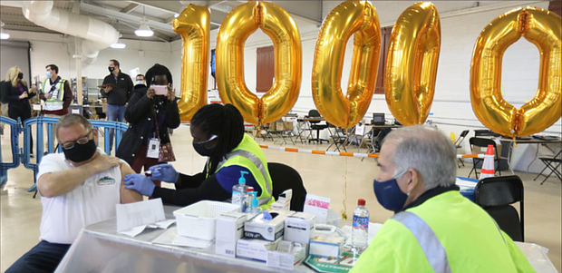 Tom Leonard, 65, owner of Tom Leonard’s Farmer’s Market in Short Pump, holds up his sleeve as nurse Antwon Agee administers his second shot of the Pfizer vaccine last Saturday. Mr. Leonard received the 100,000th dose of the vaccine given at clinics at the Richmond Raceway. “I feel pretty special today,” he said.