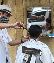 A roadside barber in Hanoi wearing a protective face mask in February of 2020 -- long before the US recommended face masks.
Mandatory Credit:	MANAN VATSYAYANA/AFP/AFP via Getty Images