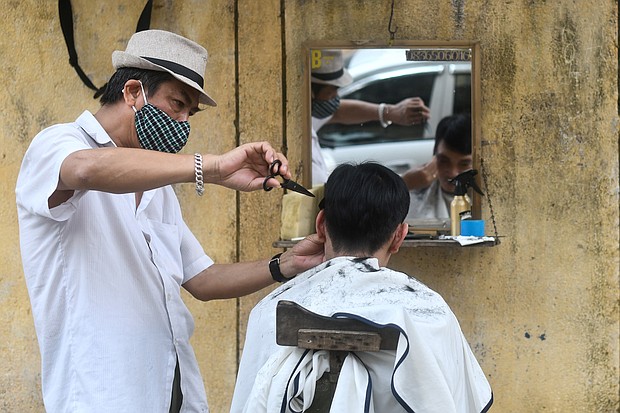 A roadside barber in Hanoi wearing a protective face mask in February of 2020 -- long before the US recommended face masks.
Mandatory Credit:	MANAN VATSYAYANA/AFP/AFP via Getty Images
