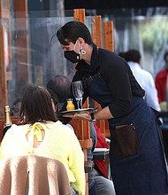 Some say full herd immunity may not be necessary for life to look more normal. A waiter at The Dorian serves champagne to guests who are dining outside on April 02, 2021 in San Francisco, California.
Mandatory Credit:	Justin Sullivan/Getty Images
