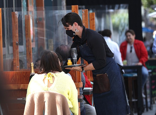 Some say full herd immunity may not be necessary for life to look more normal. A waiter at The Dorian serves champagne to guests who are dining outside on April 02, 2021 in San Francisco, California.
Mandatory Credit:	Justin Sullivan/Getty Images