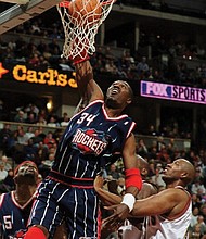 In this Jan. 28, 2000, file photo, Houston Rockets center Hakeem Olajuwon dunks the ball over Denver Nuggets center Popeye Jones during a game in Denver.