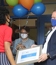 Ashley S. Bland is surprised last Friday with a plaque and roses presented by Richmond Schools Superintendent Jason Kamras, right, and Richmond Mayor Levar M. Stoney. She thought she was attending a Teacher Appreciation Week event at John B. Cary Elementary School when she was surprised with the Teacher of the Year Award.