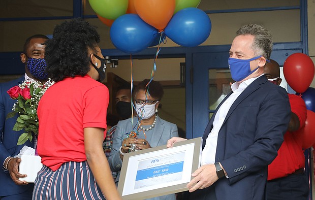 Ashley S. Bland is surprised last Friday with a plaque and roses presented by Richmond Schools Superintendent Jason Kamras, right, and Richmond Mayor Levar M. Stoney. She thought she was attending a Teacher Appreciation Week event at John B. Cary Elementary School when she was surprised with the Teacher of the Year Award.