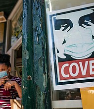 New York will adopt the US Centers for Disease Control and Prevention's guidelines to not require masks or social distancing for vaccinated people beginning Wednesday. A customer exits a corner market while wearing a protective mask in the retail shopping district of the SoHo neighborhood of the Manhattan borough of New York, Friday, May 14, 2021.
Mandatory Credit:	John Minchillo/AP