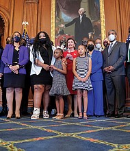 Members of George Floyd’s family and their attorney, Benjamin Crump, right, stand Tuesday in the Rayburn Room of the U.S. Capitol with House Speaker Nancy Pelosi, in red, and Rep. Karen Bass, next to her in blue.