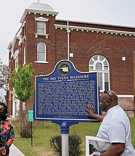 Tiffany Crutcher, left, and Chief Egunwale Amusan talk about a sign commemorating Tulsa’s original Black Wall Street during a tour on April 12.