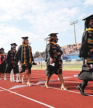 Jamal Meekins, 22, right, a psychology major from Surry County, walks with fellow graduates during the procession Sunday at Virginia State University’s commencement in Rogers Stadium for the classes of 2020 and 2021. Mr. Meekins, who earned his degree this spring, will begin nursing school next week.