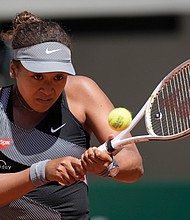 Japan’s Naomi Osaka returns the ball to Romania’s Patricia Maria Tig during their first round match Sunday at the French Open at Roland Garros stadium in Paris.