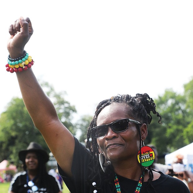 Claudia Clarke raises her fist in a show of support and solidarity with the messages delivered by local leaders at the “Love and Legacy Juneteenth Jubilee Celebration” at the Landing at Fountain Lake in Byrd Park  The event, organized by Sherri Robinson of ShowLove LLC, featured music, dance, entertainment, children’s activities and information about community resources.