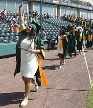 Kym Idella Jeter waves to family and friends in the stands as she walks out with Huguenot High School’s new graduates at the end of Monday morning’s ceremony at The Diamond on Arthur Ashe Boulevard. Huguenot’s was the first of eight Richmond high school commencements over three days at the ballpark.