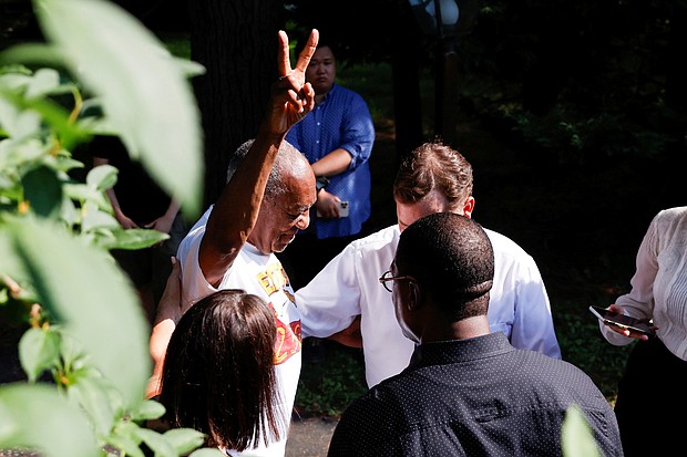 Bill Cosby flashes a victory sign Wednesday outside his home in Elkins Park, Penn., after the state’s highest court overturned his sexual assault conviction and ordered him released from prison immediately.