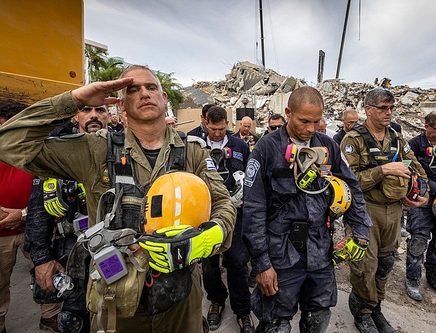 Members of search and rescue teams gather for a moment of silence and prayer at the memorial to the victims in the collapsed 12-story Champlain Towers South condo building.
Mandatory Credit:	Jose A Iglesias/Pool/Getty Images