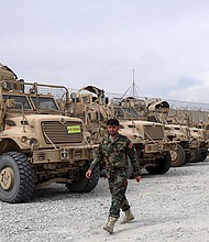 An Afghan army soldier walks past Mine Resistant Ambush Protected vehicles that were left after the American military left Bagram air base, north of Kabul, Afghanistan, on July 5.
Mandatory Credit:	Rahmat Gul/AP