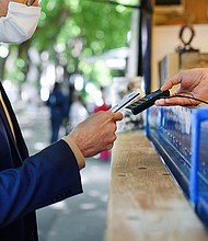 A man pays at a coffee stall. The US economy is showing signs of recovery. That could also mean spending more money on activities that people may not have done in a while -- like going to the movies, dining out or taking a vacation.
Mandatory Credit:	Halfpoint Images/Moment RF/Getty Images