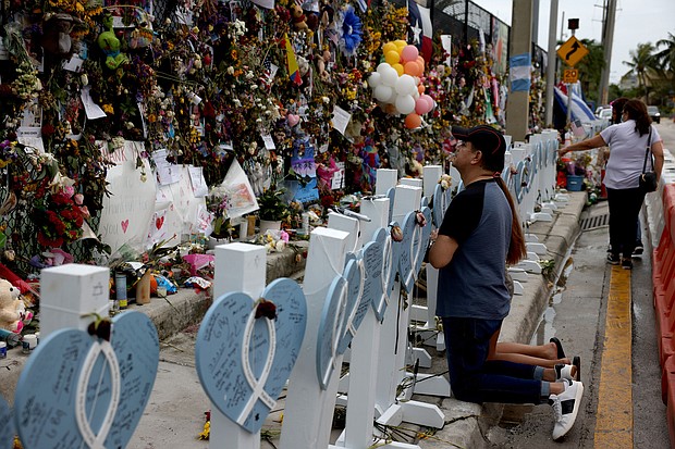 People pray at the memorial to the victims of the collapsed Champlain Towers South condo building following a severe thunderstorm on July 12.
Mandatory Credit:	Anna Moneymaker/Getty Images