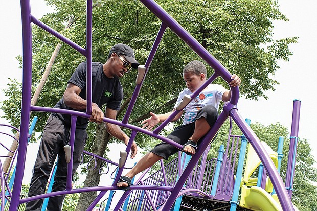 Fun with Dad/Rashe Peoples Jr., 6, takes on the challenge of climbing on playground equipment with the knowledge his dad, Rashe Peoples, has his back. The father and son enjoyed time together last Saturday at Abner Clay Park in Jackson Ward.
