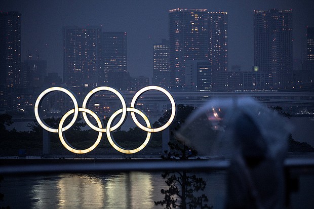 A woman walks past the Olympic Rings lit up at dusk in the rain, on the Odaiba waterfront in Tokyo on July 9. An unnamed US female gymnast has tested positive for Covid-19, Inzai city official Takamitsu Ooura told CNN.
Mandatory Credit:	CHARLY TRIBALLEAU/AFP/Getty Images
