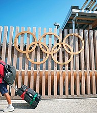 A man walks past Olympic rings at the entrance to Olympic Village.
Mandatory Credit:	Michael Kappeler/picture-alliance/dpa/AP