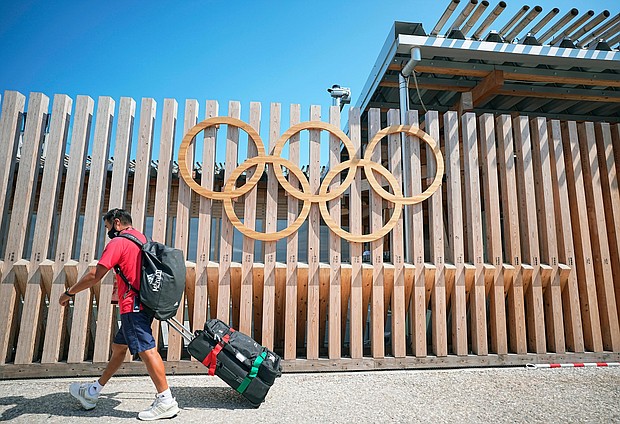 A man walks past Olympic rings at the entrance to Olympic Village.
Mandatory Credit:	Michael Kappeler/picture-alliance/dpa/AP