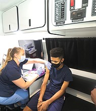 Joshua Thompson, 14, gets the first shot of the Pfizer vaccine from nurse Christina Carney in a Richmond Health District mobile clinic van on Tuesday. His mother, a registered nurse, brought him to the pop-up vaccination event at Silk Hair Studio on West Broad Street. The salon provided space for people to be registered and to wait during the 15-minute post-vaccination observation period.