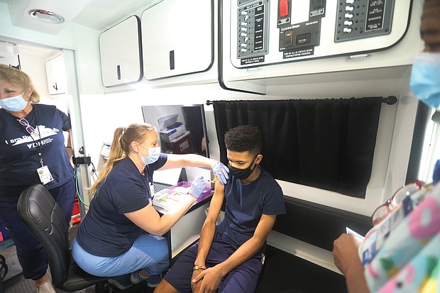 Joshua Thompson, 14, gets the first shot of the Pfizer vaccine from nurse Christina Carney in a Richmond Health District mobile clinic van on Tuesday. His mother, a registered nurse, brought him to the pop-up vaccination event at Silk Hair Studio on West Broad Street. The salon provided space for people to be registered and to wait during the 15-minute post-vaccination observation period.