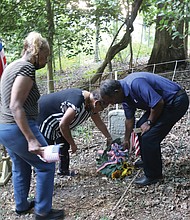 Honoring a Buffalo Soldier/Descendants of Moses Bradford Jr. of Henrico County, a Buffalo Soldier who served in the 25th Infantry during the Spanish-American War, place a wreath on his grave during a twilight memorial service at the Sons and Daughters of Ham Cemetery near Bandy Field in Henrico County on July 28. The family members, from left, Diane Winston Jones, Linda Truman Nash and Spencer Truman, participated in the local commemoration on National Buffalo Soldiers Day, which honors the contributions of some of the earliest African-American troops in the U.S. military. The commemoration included a three-volley salute by members of the Veterans of Foreign Wars Post 9808 in Mechanicsville, and a flag presentation, below, by Najiek Harris, 15, left, and Christian Hicks, 13, of Scout Troop 432 in Church Hill. Pvt. Bradford, who fought during the Battle of El Caney in Cuba on July 1, 1898, suffered a heat stroke while in Cuba and was returned home as a casualty of war. He was honorably discharged from the military in 1899, and went on to live to the age of 55, succumbing in 1925. His government-issued gravestone is one of only two left in the historic African-American cemetery that is located on an acre of land purchased by the Ham Council in 1873 and now is listed with the Virginia Department of Historic Resources.