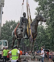 A crane hauls away the massive, 100-year-old statue of Confederate Gen. Thomas “Stonewall” Jackson from its pedestal at Monument Avenue and Arthur Ashe Boulevard during a downpour on July 1, 2020.