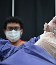 A patient looks on as a registered nurse prepares a syringe with a dose of Pfizer COVID-19 vaccine at a vaccination site in the Queens borough of New York, NY, July 30, 2021.
Mandatory Credit:	ANTHONY BEHAR/SIPA USA/AP