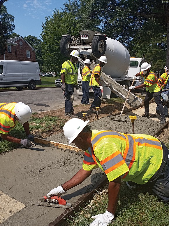 John Williams, center, a 13-year veteran of the city Department of Public Works, is part of a crew replacing sidewalks …