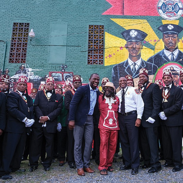 Scores of people turned out Aug. 6 for the official unveiling of the mural honoring the first Black firefighters hired by the City of Richmond. The 10 trailblazers were hired July 1, 1950, and were stationed at Engine Company No. 9 at 5th and Duval streets in Jackson Ward. The commemorative mural was done by local artists Sir James Thornhill, Jason Ford and Kevin Orlosky, and is situated on the side of the Mocha Temple No. 7 Shrine building at 613 N. 2nd St. in Jackson Ward. Members of Mocha Temple pose for a group photo with, at center, Mayor Levar M. Stoney; Mr. Thornhill; and Fire Chief Melvin D. Carter. The unveiling was the kickoff of a weekend of activities sponsored by Engine Company #9 and Associates remembering and honoring the original firefighters.
