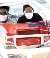 Fraternal twins Aniyah Rawl, left, and her brother, Xavier Rawl, 14, pause for a portrait through the frame of the Dodge Daytona Coupe 500 R that they are helping to build under the tutelage of pioneering aviator Barrington Irving with The Flying Classroom project and Richmond Public Schools. The hands-on work is taking place at Richmond Raceway.