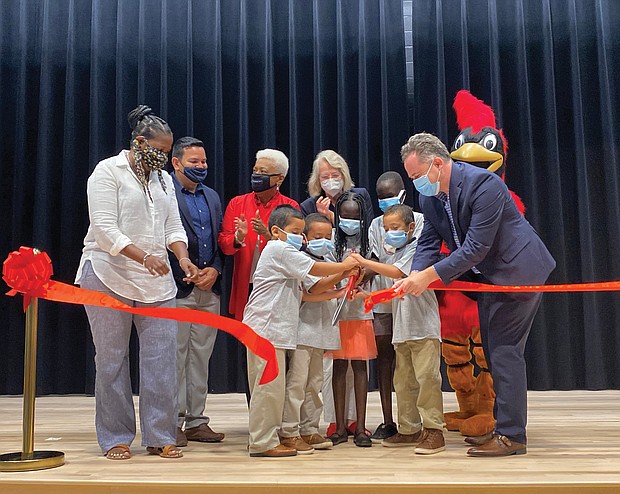Celebrating Cardinal Elementary’s dedication with a ribbon-cutting are, several students and, from left, School Board member Nicole Jones; Principal Juvenal E. Abrego- Meneses; School Board Chairwoman Cheryl L. Burke; Delegate Betsy B. Carr; Superintendent Jason Kamras and the Cardinal mascot.