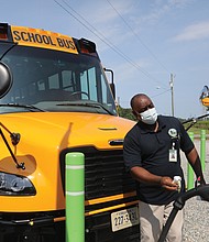 New wheels for Chesterfield schools/Al Parham, supervisor of Chesterfield County Public Schools’ bus fleet, wipes off the plug-in station for the school system’s two new electric school buses during a “Plug-in Ceremony” Aug. 12 at the county’s bus maintenance facility, 7300 Walmsley Blvd. School and county officials, along with officials from Dominion Energy, attended the event held to show off the two new vehicles that were delivered in May. Chesterfield is the first municipality in Metro Richmond to receive the electric school buses through a program sponsored by Dominion Energy. Under the program, school districts pay no more for the electric buses than they would for a diesel model. The program also covers the cost of the charging stations. The first 50 buses were provided under the program in 2020 to 14 school districts in various parts of the state. (photo: Regina H. Boone/Richmond Free Press)