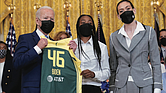 President Joe Biden, left, poses Monday for a photo with Seattle Storm’s Jewell Lloyd, center, and Breanna Stewart, right, during an event in the East Room of the White House to celebrate their 2020 WNBA Championship.