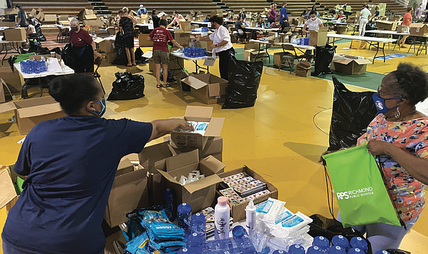 On Tuesday, community volunteers Tracie Tucker, left, and Barbara Burton, the parent of two RPS graduates, participated in a “PPE Party Packing” effort at the Arthur Ashe Jr. Athletic Center next to The Diamond to pack kits of personal protective equipment, or PPE, for students.
Also joining in the effort were RPS teachers and staff and Richmond social workers and employees from the Office of Community Engagement. Each kit contains hand sanitizer, a mask, a water bottle, a thermometer and a magnet printed in both English and Spanish with the symptoms to check for during the pandemic. The group hoped to pack at least 25,000 PPE kits that will be given to students on the opening day.
Gov. Northam and the state health commissioner have issued public health orders for all Virginia students in kindergarten through 12th grade to wear masks inside schools. The goal is for students to stay healthy and avoid the coronavirus.