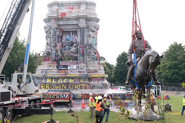Workers carefully lower to the ground Wednesday the 12-ton bronze statue of Confederate Gen. Robert E. Lee from the large stone pedestal on Monument Avenue where it has stood since 1890.