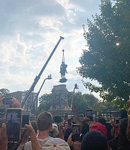 Onlookers cheer and take pictures as the Lee statue is lowered to the ground and dismantled by workers on Wednesday before being transported to a warehouse. The state will decide what to do with the statue and its large stone pedestal.