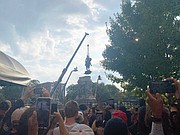 Onlookers cheer and take pictures as the Lee statue is lowered to the ground and dismantled by workers on Wednesday before being transported to a warehouse. The state will decide what to do with the statue and its large stone pedestal.