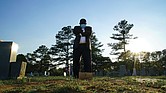 Mortician Shawn Troy stands at the grave of his father, William Penn Troy Sr., at Hillcrest Cemetery outside Mullins, S.C., on Sunday, May 23, 2021. The elder Troy, who developed the cemetery, died of COVID-19 in August 2020, one of many Black funeral directors to succumb to the pandemic. “I don’t think I’ll ever get over it,” he said. “But I’ll get through it.”