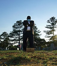 Mortician Shawn Troy stands at the grave of his father, William Penn Troy Sr., at Hillcrest Cemetery outside Mullins, S.C., on Sunday, May 23, 2021. The elder Troy, who developed the cemetery, died of COVID-19 in August 2020, one of many Black funeral directors to succumb to the pandemic. “I don’t think I’ll ever get over it,” he said. “But I’ll get through it.”