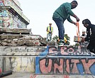 Devon Henry, whose company, Team Henry Enterprises, took down the Monument Avenue statue of Confederate Gen. Robert E. Lee, works with Grindly Johnson, Virginia’s secretary of administration, to place a new time capsule into the base around the pedestal.