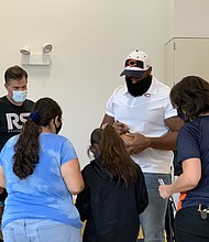 Chicago Bears defensive lineman Akiem Hicks signs footballs for the children and families during an event at SOS Children’s Villages Chicago where 170 pairs of shoes were donated. Photo by Tia Carol Jones