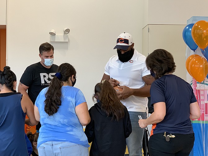 Chicago Bears defensive lineman Akiem Hicks signs footballs for the children and families during an event at SOS Children’s Villages Chicago where 170 pairs of shoes were donated. Photo by Tia Carol Jones
